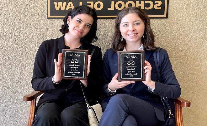 Holland and Goeke sitting with awards